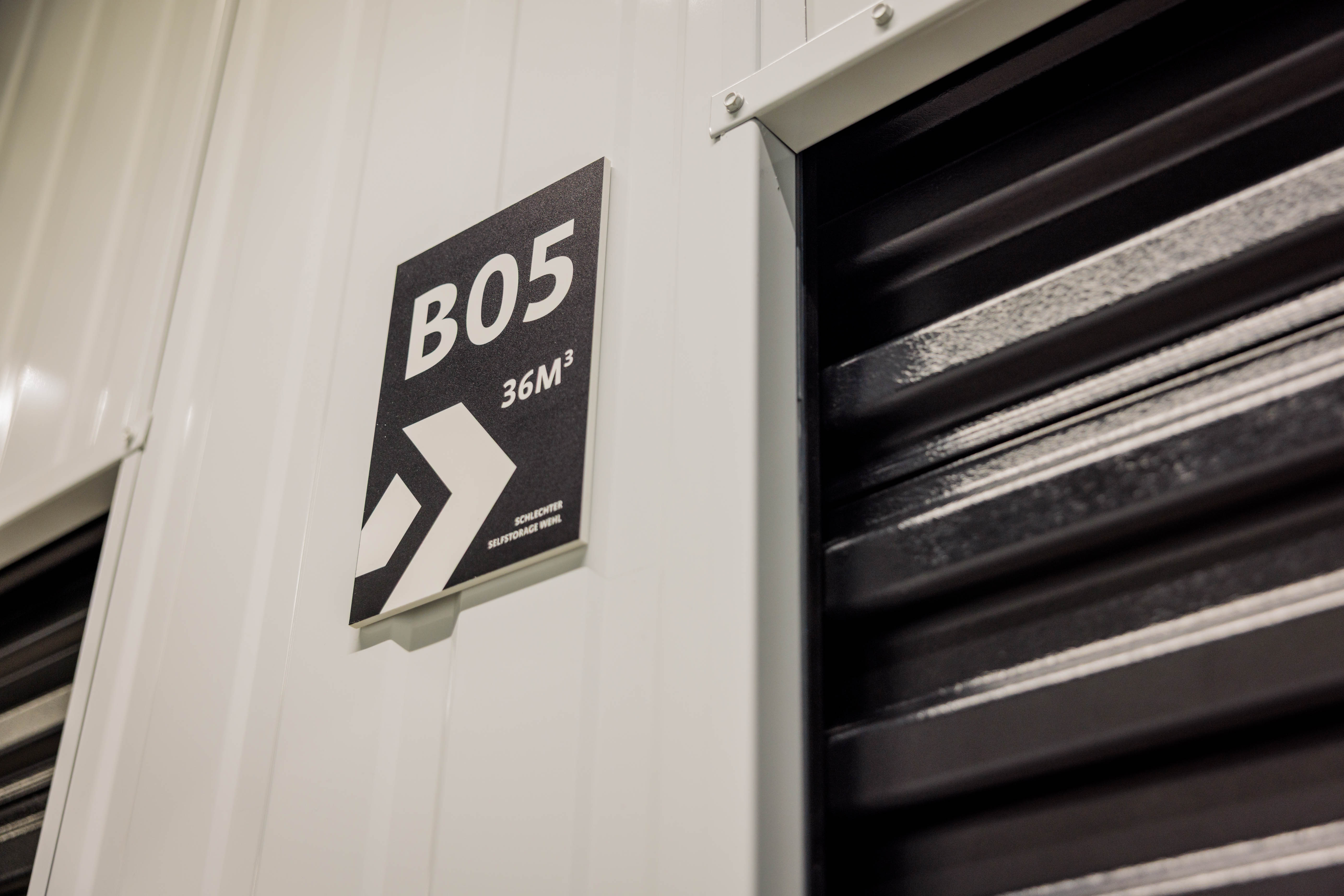 Naambord van opslagruimte B05 naast een roldeur bij Schlechter Selfstorage