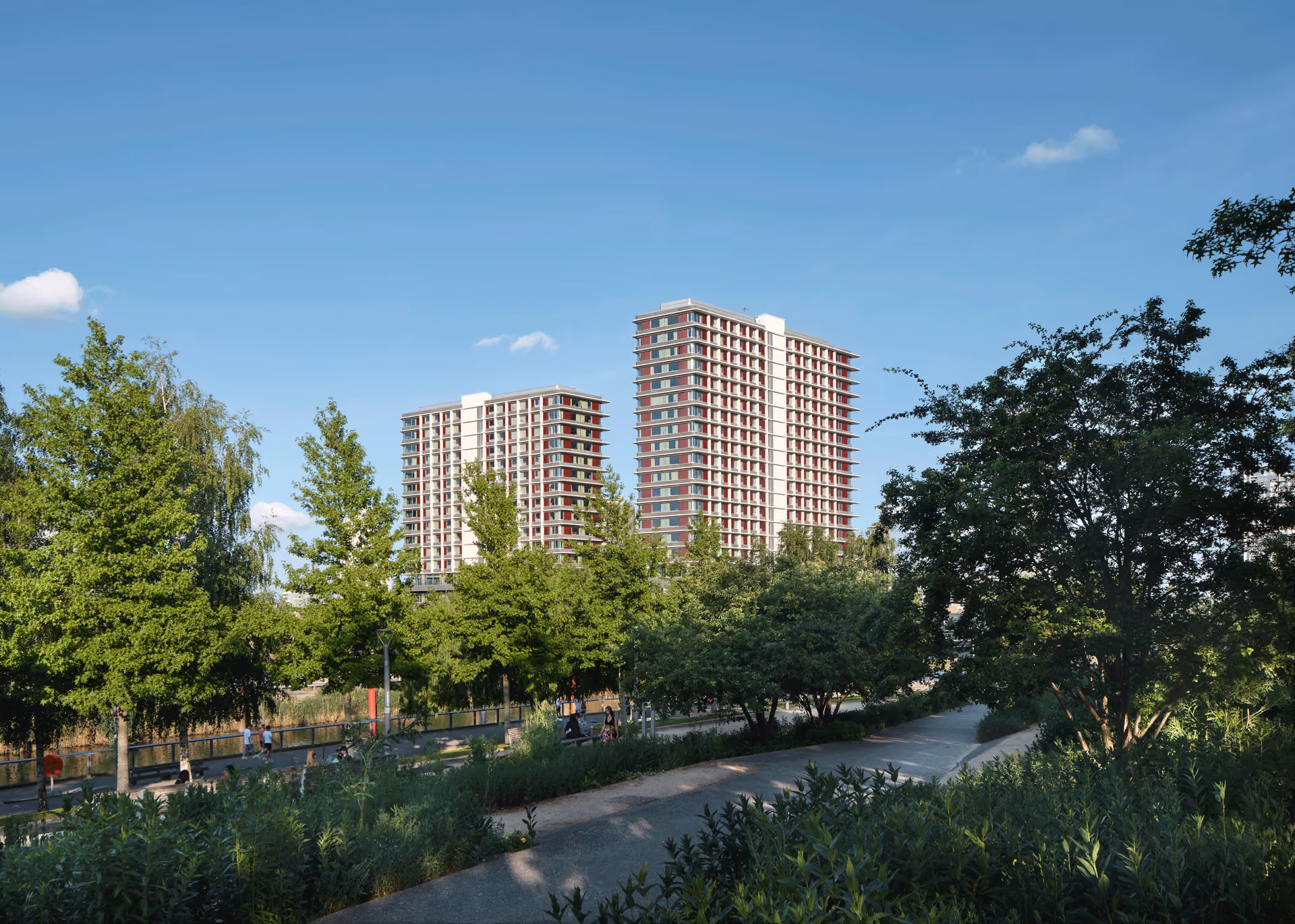 Pool Street West towers in brick rising behind a landscaped park with mature trees and water.