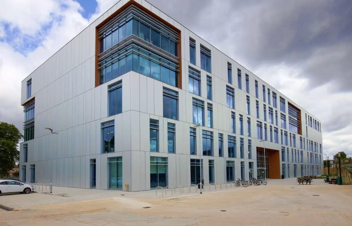 Richmond College building clad in pale glazed panels and full-height windows under a grey sky.