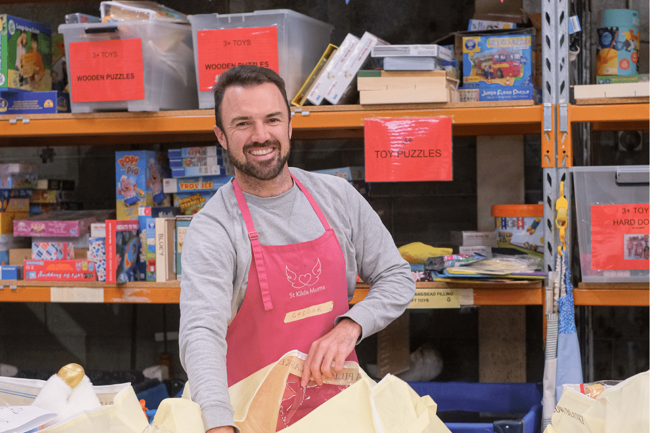 Smiling man volunteers to sort toys for disadvantaged kids.