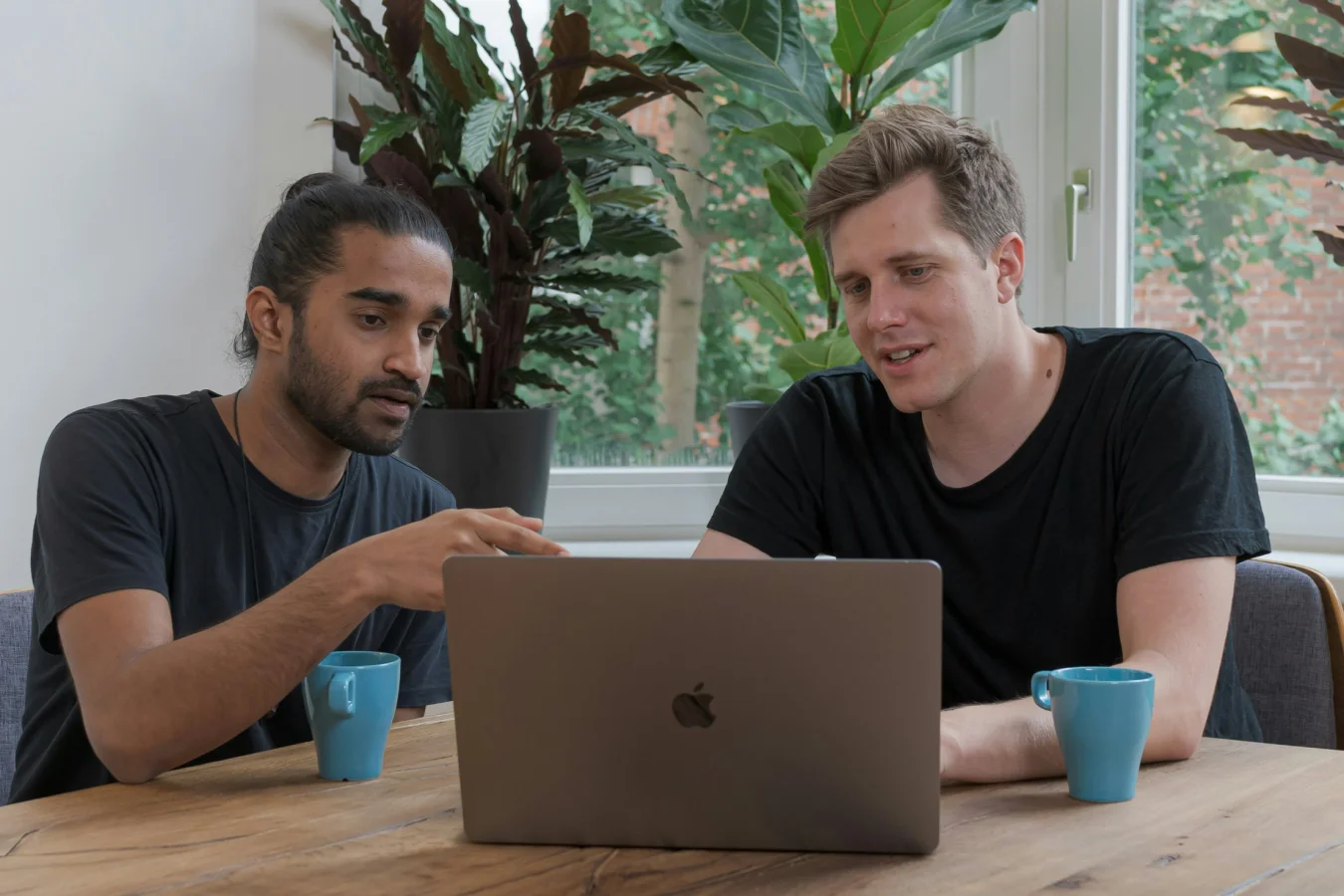 Three colleagues collaborating around a laptop