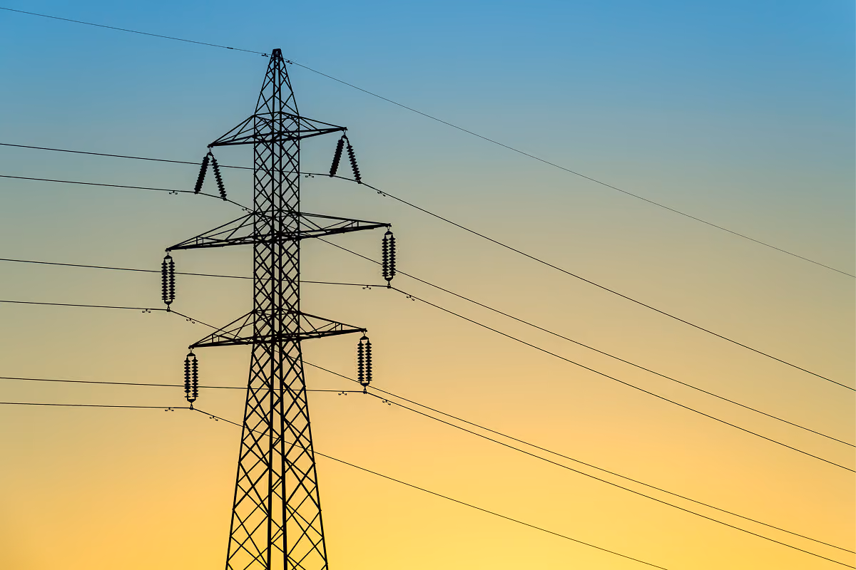 Electricity pylons silhouetted against a sunset