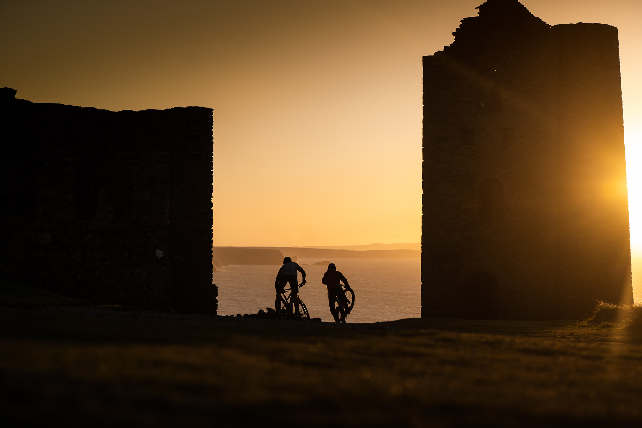 Cyclists riding through coastal ruins at sunset