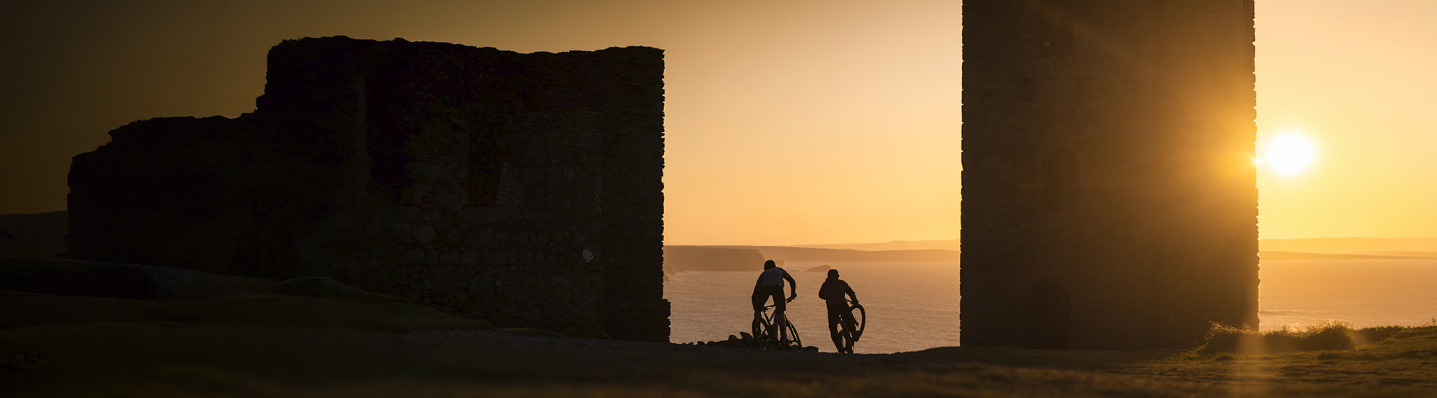 Cyclists crossing a coastal landscape at sunset