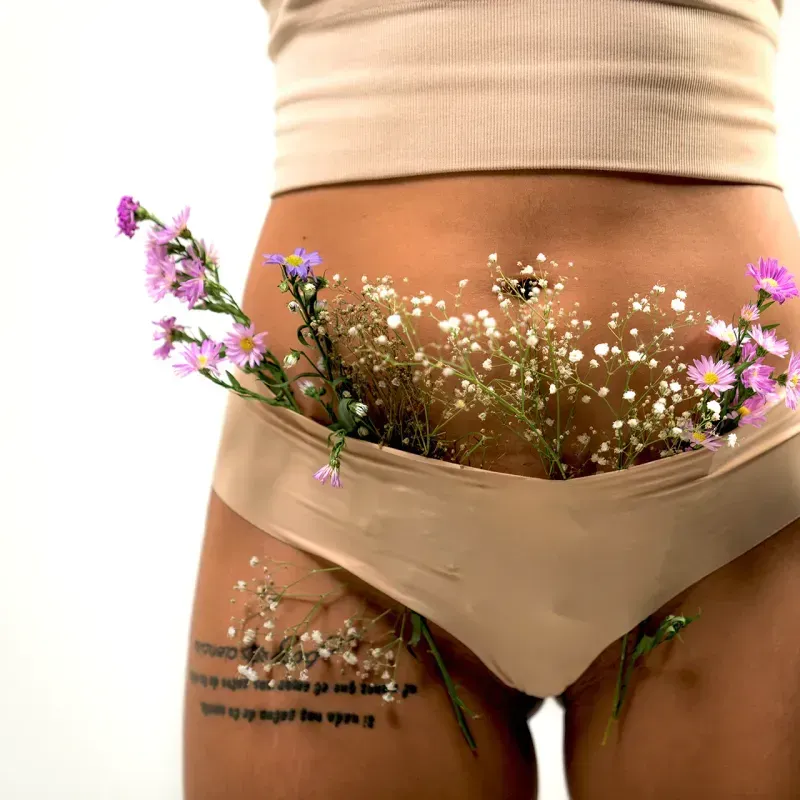 Close-up of a woman's lower torso with flowers in her underwear, symbolizing vaginal health.
