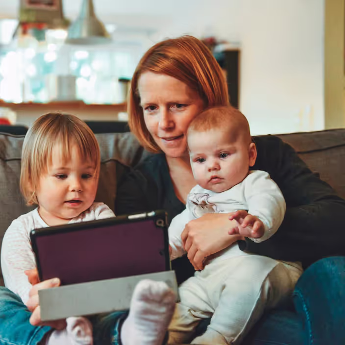 A mom sits on the couch with her toddler and baby looking at Tiny Health gut health test results