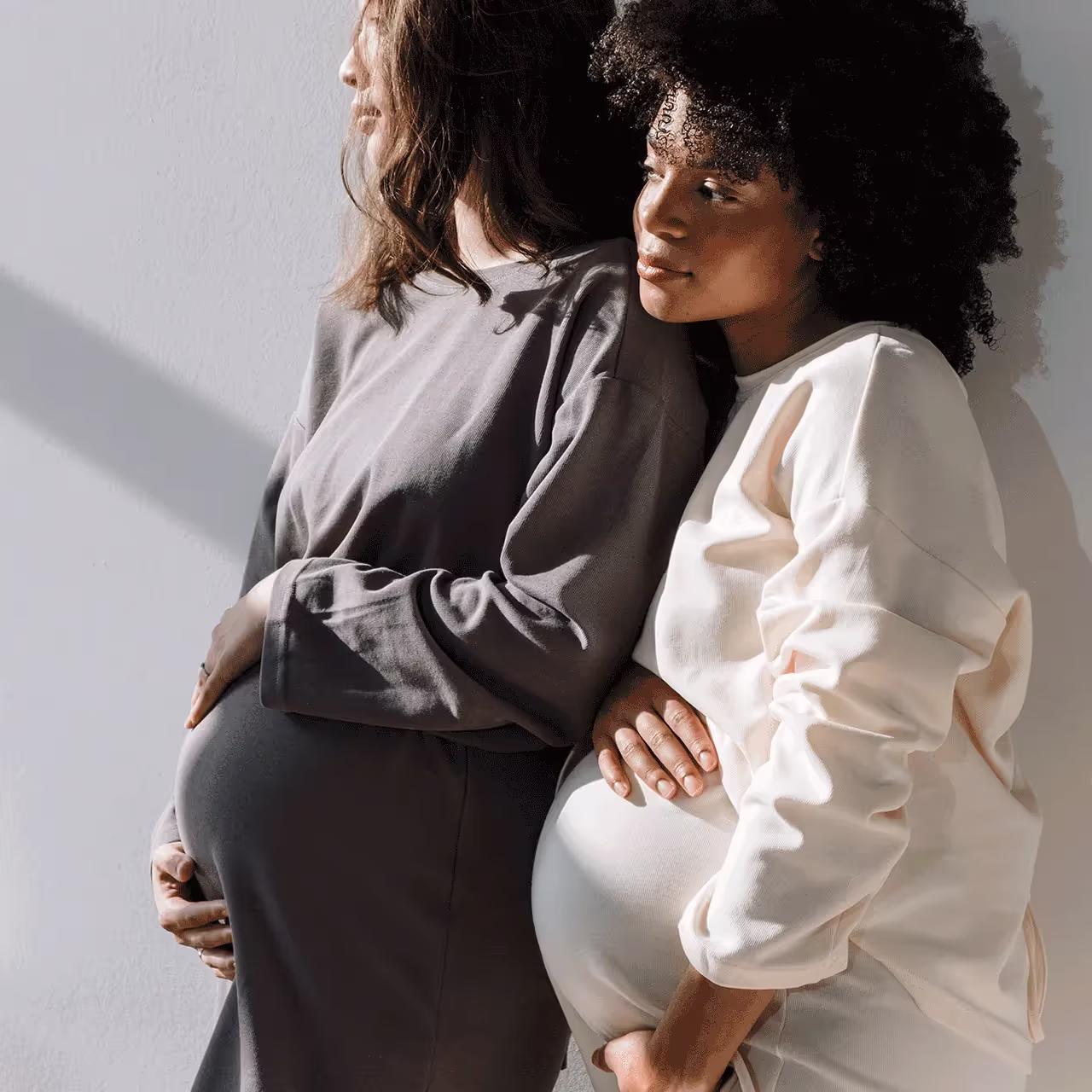Two pregnant women leaning on each other, representing the significance of Group B Strep awareness in pregnancy
