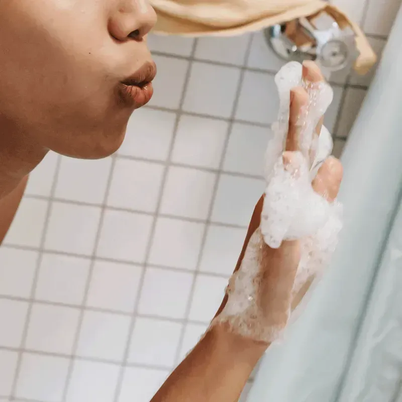 Close-up of a woman blowing bubbles from her soaped hand