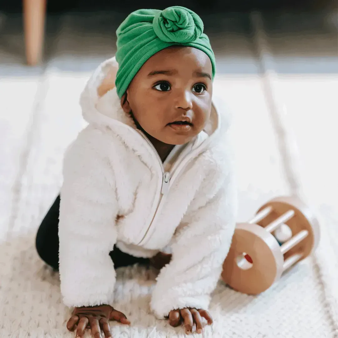 A baby crawling on the carpeted floor of a daycare