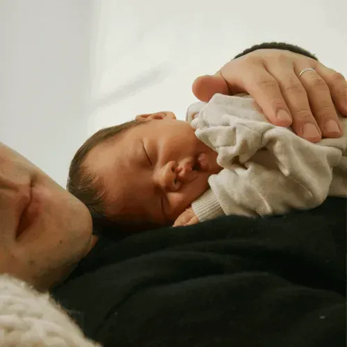 Newborn sleeping peacefully on a parent's chest, highlighting the importance of care in preventing preterm birth