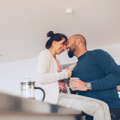 Couple embrace in the kitchen, highlighting the exchange of microbiomes through physical closeness