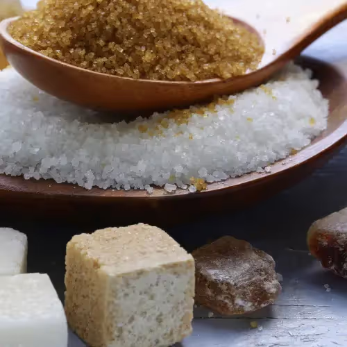 A variety of natural and artificial sweeteners, including brown sugar, white sugar, and cubes, displayed on a wooden plate.