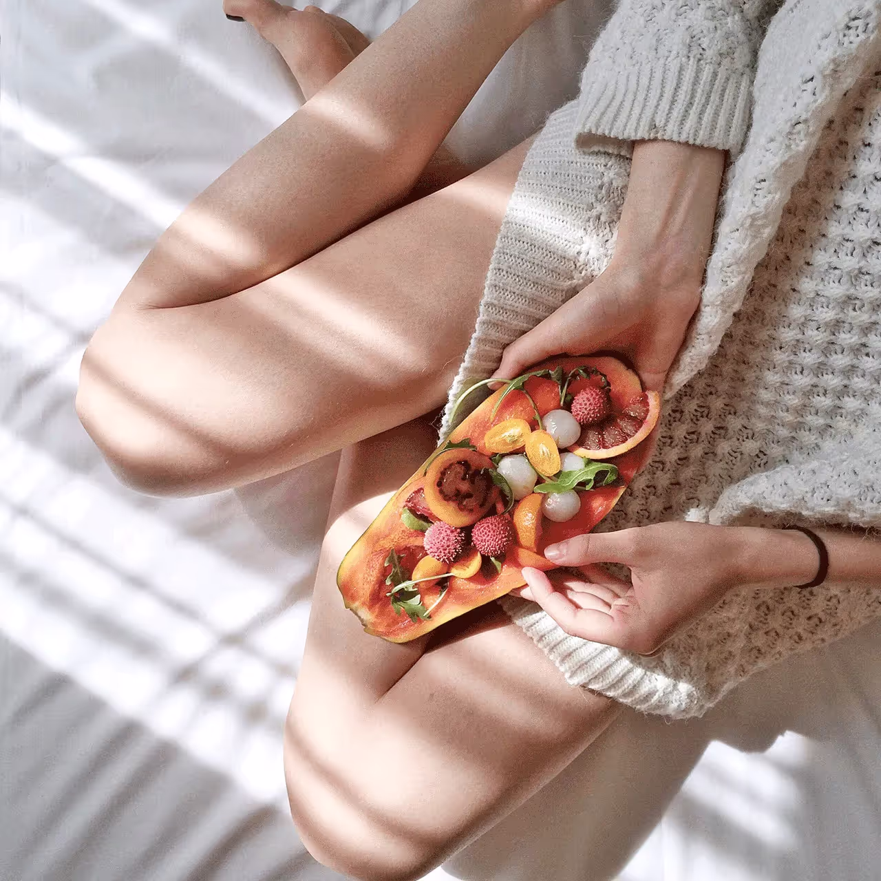 A woman holding a papaya filled with various fruits, symbolizing a vaginal yeast infection