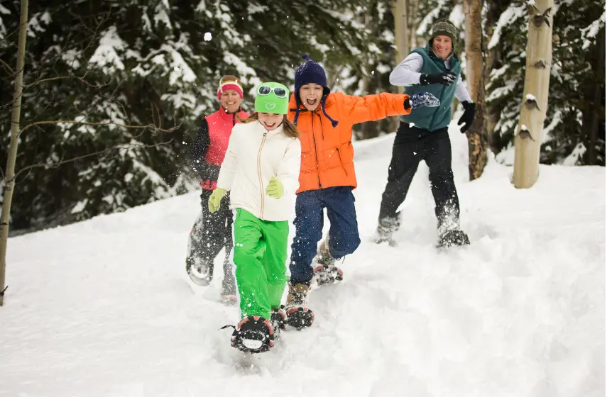 A joyful family snowshoeing together in the woods, enjoying an active winter day in the snow.
