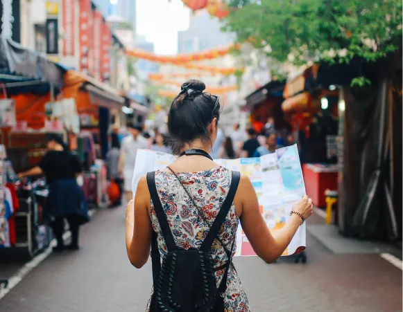 a woman staring at a map on a public market in the street. 