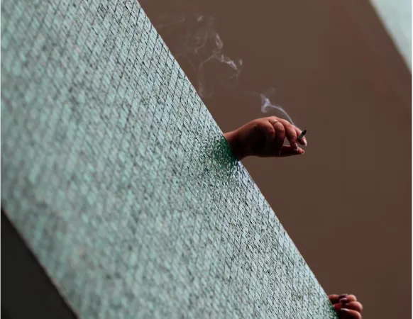 hands holding a cigarette on a windows sill 