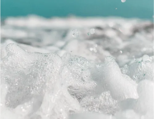 A close-up of soap bubbles on a water surface. 