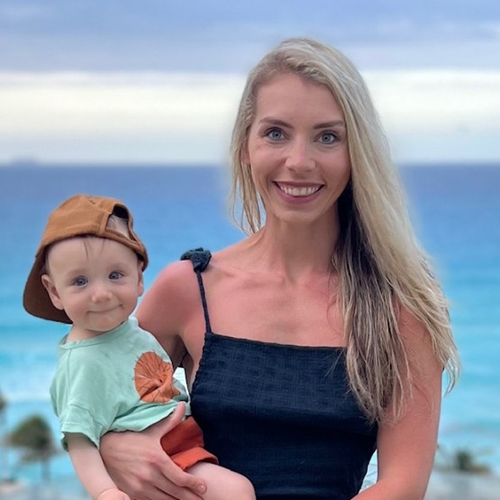 A happy mother of caucasian features and blonde hair in the beach with her baby in arms