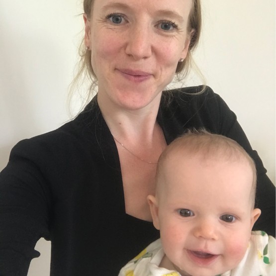 A happy mother of caucasian features smiling to camera with her baby in arms