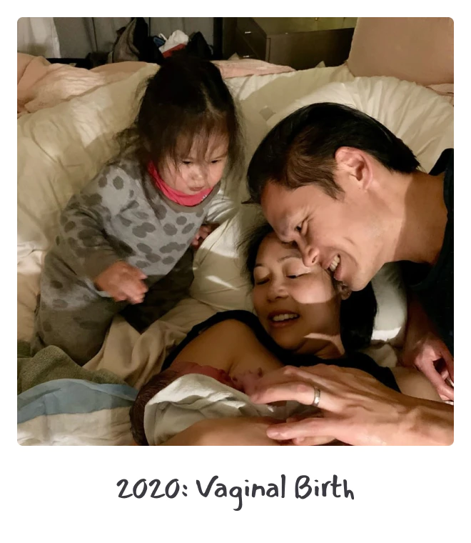 A family celebrates a vaginal birth, with a mother lying in bed holding a newborn, a father smiling closely, and an older sibling looking on with curiosity.