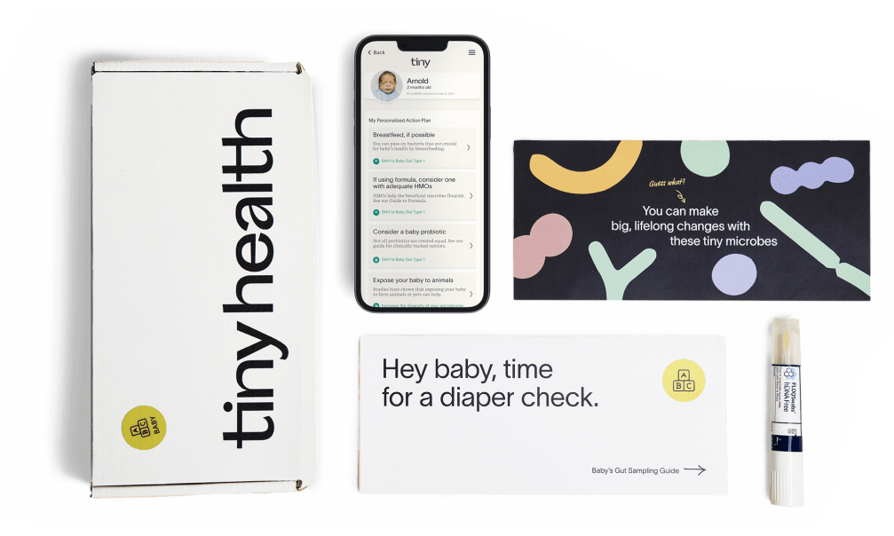 A gut health test kit laid out on a flat surface including a test box, an envelope, an instruction manual, a test swab and a phone with Tiny Health's mobile app