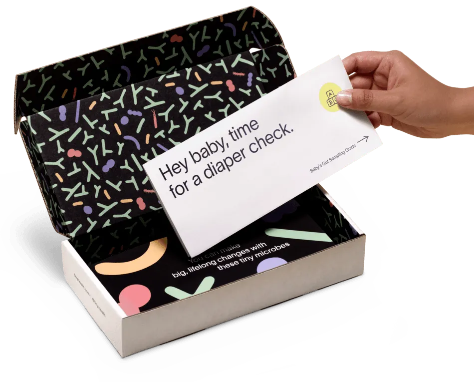 A beautiful open box with a gut health test kit and a hand reaching for a letter.