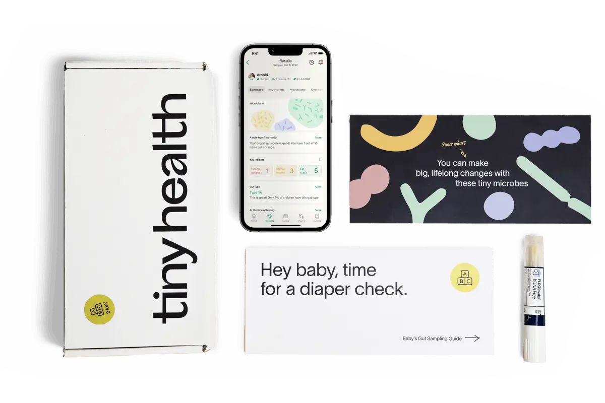 photography of a gut health test kit laid out on a flat surface including a test box, an envelope, an instruction manual, a test swab and a phone with Tiny Health's mobile app