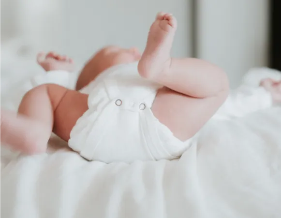 a baby lying on a bed with his feet in the air. 