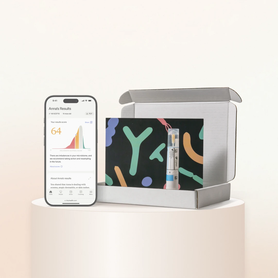 Tiny Health gut health test kit in its box, next to a phone showing a microbiome results score
