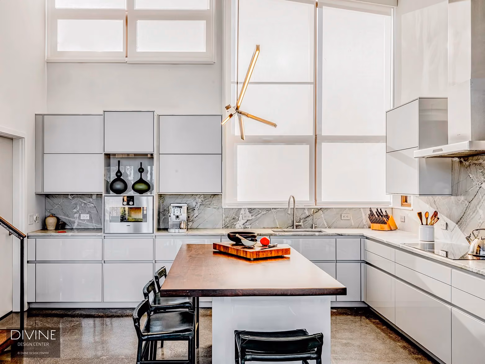Kitchen with white lacquer cabinetry, a display niche holding black ceramic vessels, a wood-topped island with a cutting board, black barstools, and a gold sculptural pendant light fixture