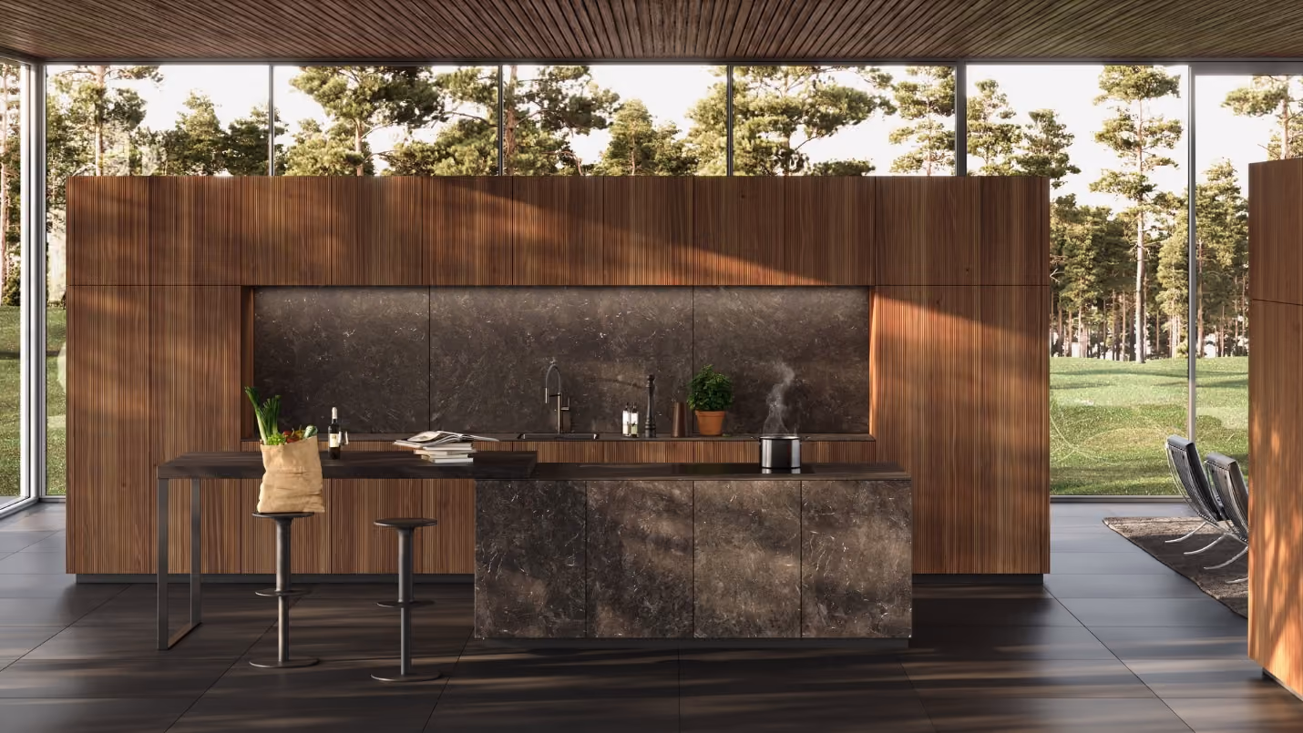 Modern kitchen with dark stone countertop island and wooden cabinetry, featuring a small table with two stools, large windows showing green trees outside.