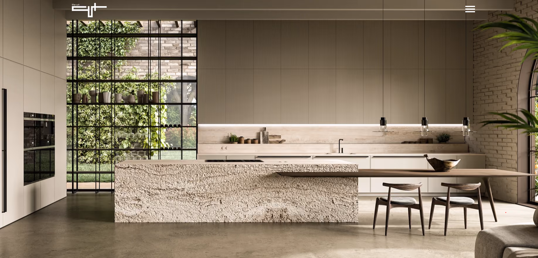 Modern kitchen with a large textured stone island, minimalist cabinetry, a wooden dining table with two chairs, large black-framed windows showcasing a green wall and outdoor greenery, and neutral-toned walls and flooring.