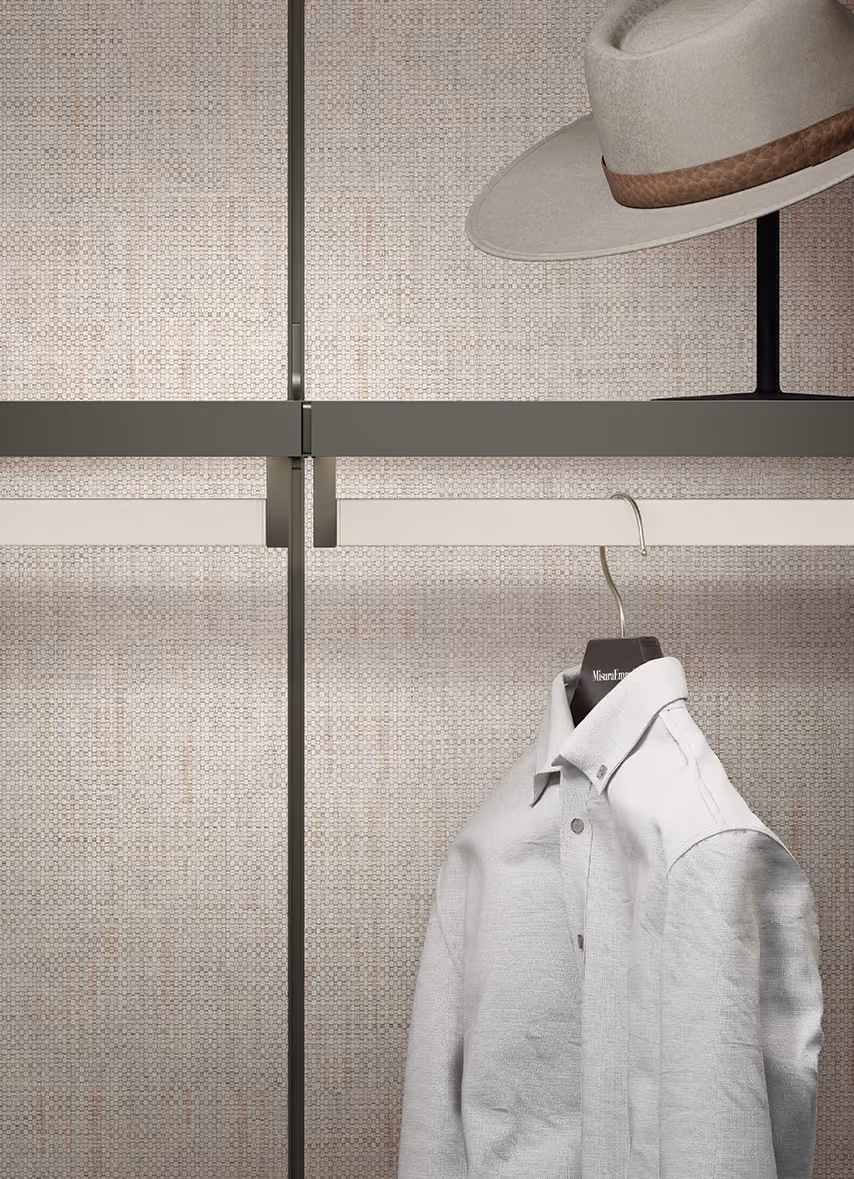 Light gray button-up shirt on a hanger and a beige hat on a stand against textured beige wall.