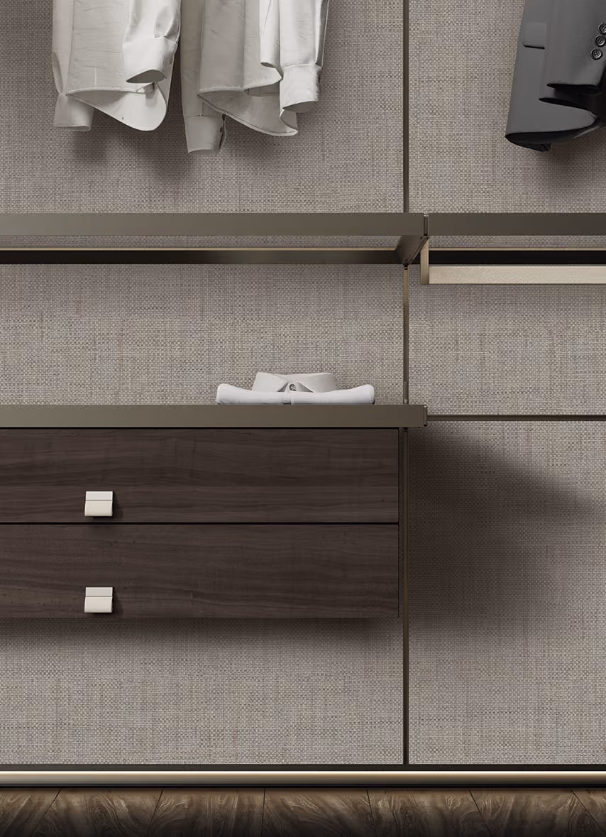 Modern closet wall with beige textured panels, hanging shirts, and dark wood drawers.