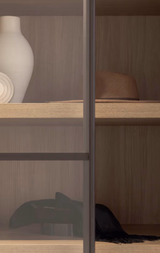 Wooden shelf with a white vase, a brown hat, a black scarf, and a black belt behind glass doors.