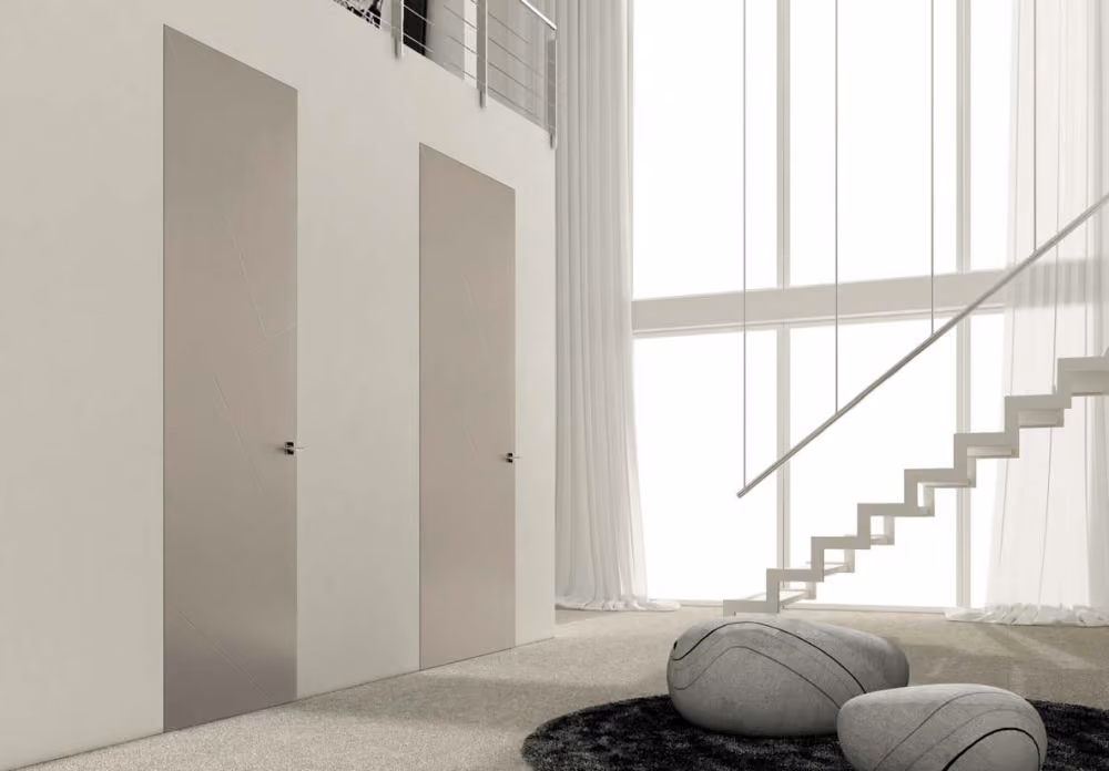 Modern minimalist interior with two closed, sleek beige doors on the left wall, a carpeted floor, two stone-like poufs on a black rug, a floating staircase with thin handrails on the right, and large windows covered with sheer white curtains.