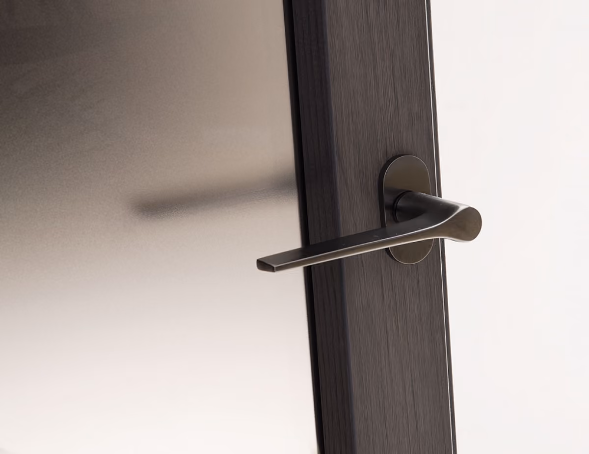 Modern black door handle mounted on a dark wood door with frosted glass panel.