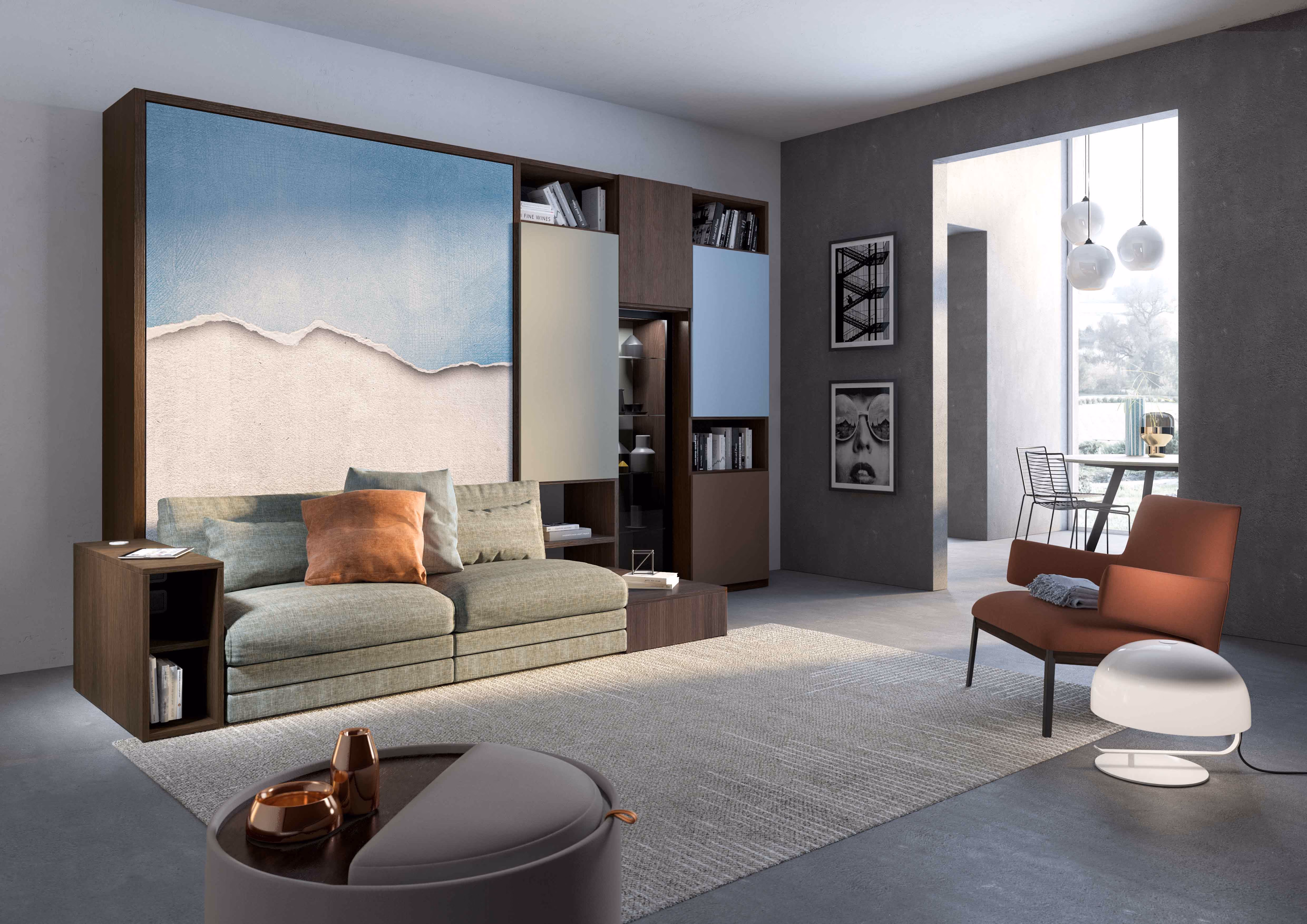 Modern living room with a beige sectional sofa featuring decorative pillows next to a wooden shelving unit with panels in blue and beige, a large gray rug, a round coffee table with decorative items, an orange lounge chair with a folded blanket, a white floor lamp, and an open doorway leading to a dining area with black metal chairs and pendant lights.