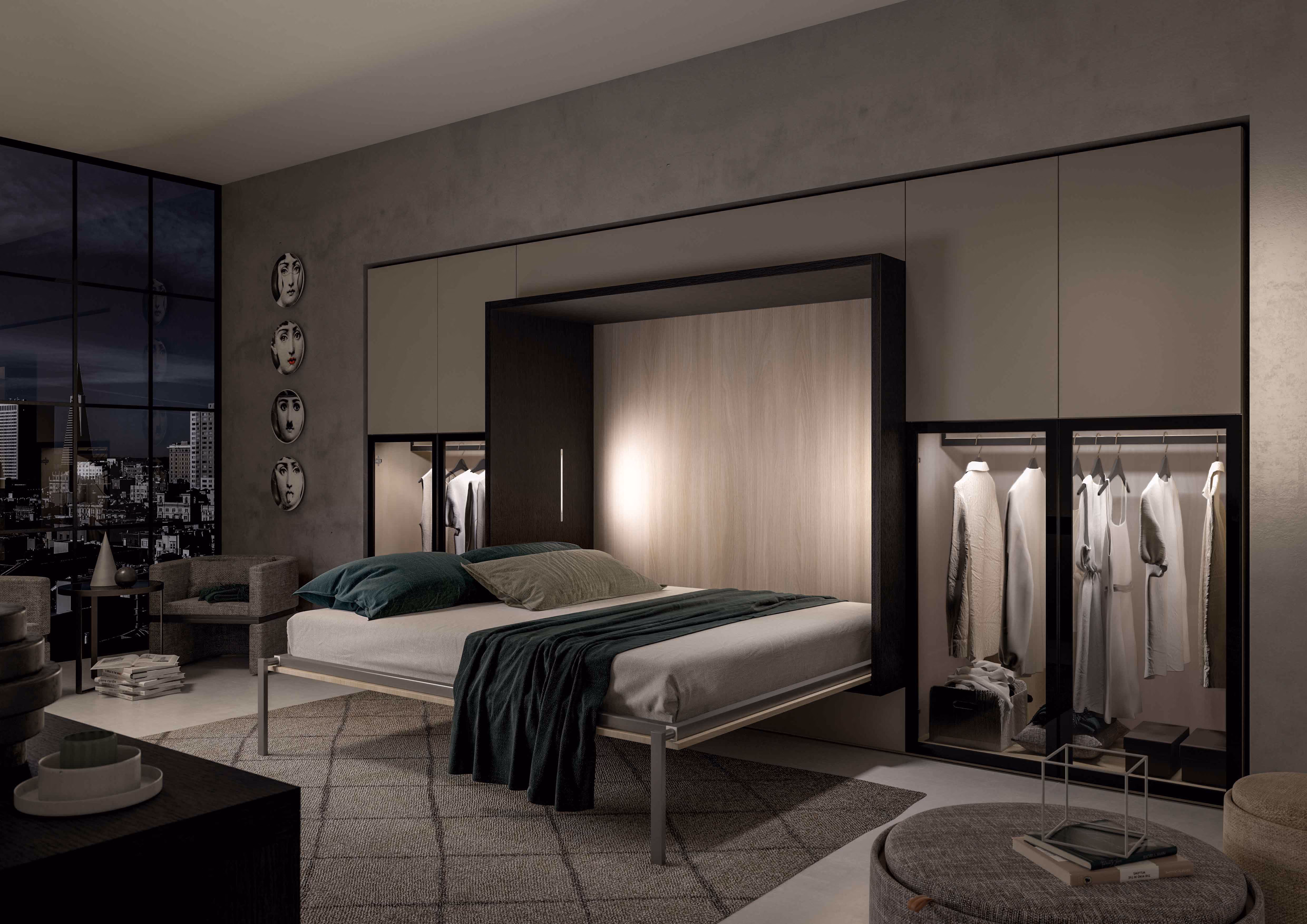 Modern bedroom with a fold-down Murphy bed that is open and made with gray bedding and green pillows, surrounded by built-in closets with illuminated glass doors displaying hanging clothes, a gray rug, and city skyline view through large windows.