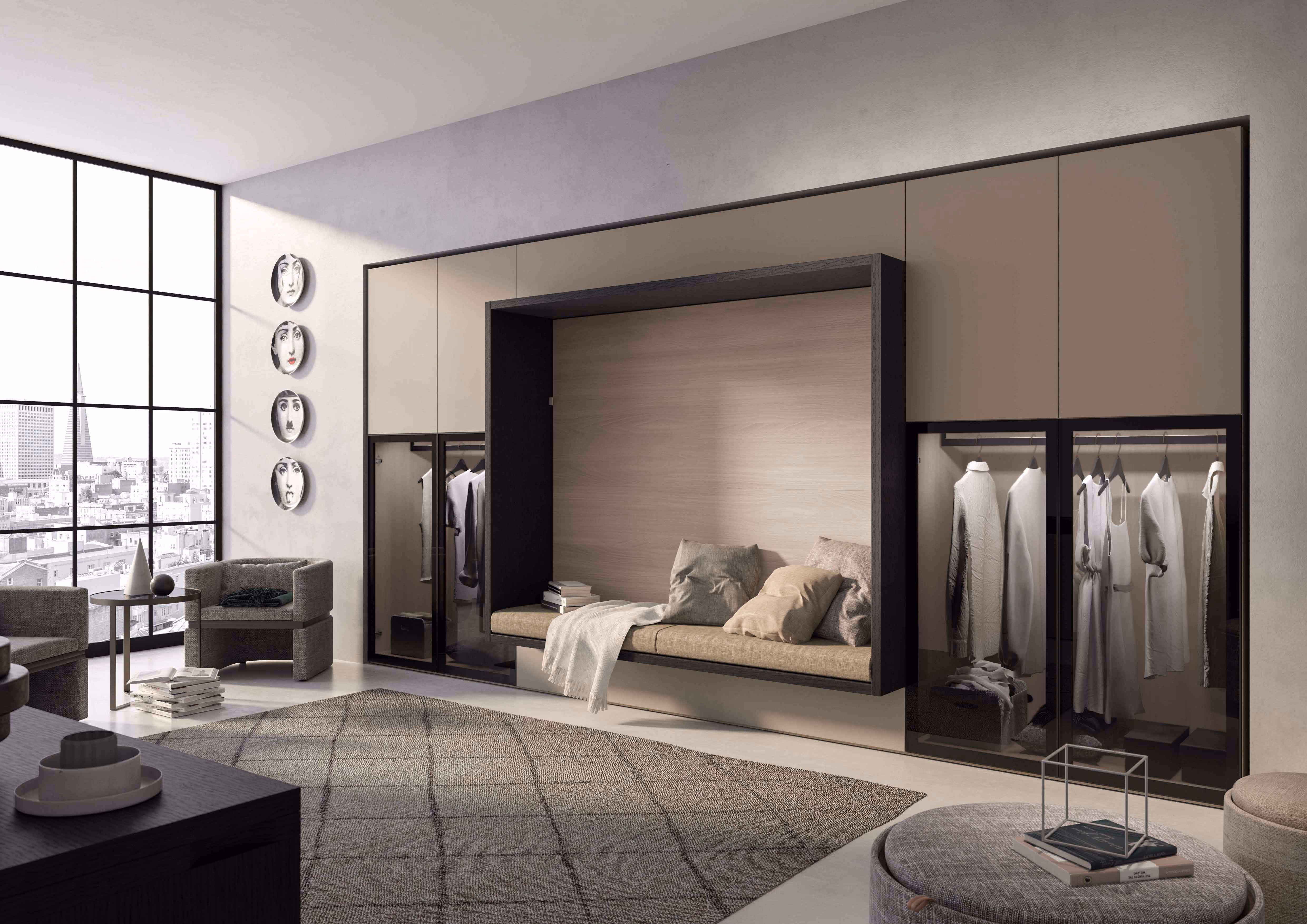 Modern bedroom with large floor-to-ceiling windows letting in natural light, a built-in wall unit featuring a recessed cushioned bench with pillows and a throw, flanked by glass-door wardrobes with hanging clothes, and a neutral-toned rug covering part of the floor.