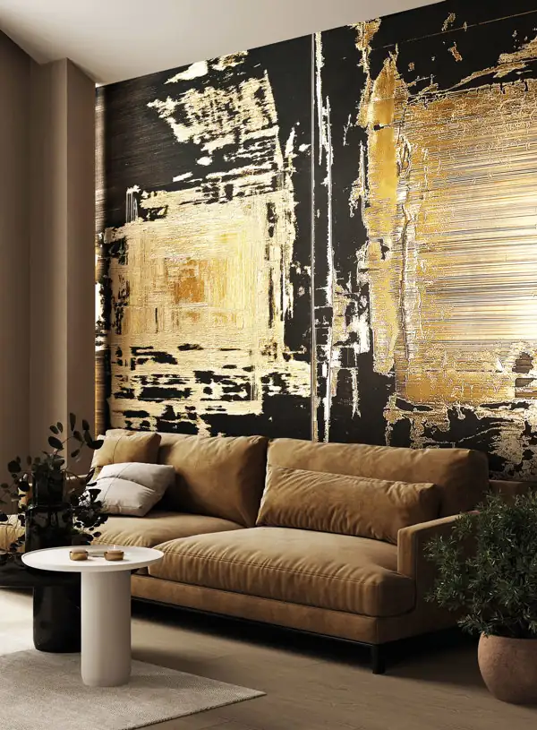 Modern living room with a large beige sofa in front of a wall featuring an abstract black and gold textured mural, a small round white coffee table, and plants on each side.