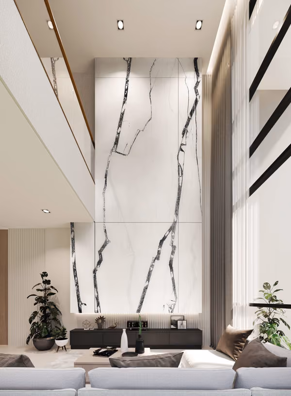 Modern living room with a tall white marble accent wall featuring dramatic black veins, a low black console with decorative items below, large windows with sheer curtains, neutral-toned sofa with pillows, and potted plants on both sides.