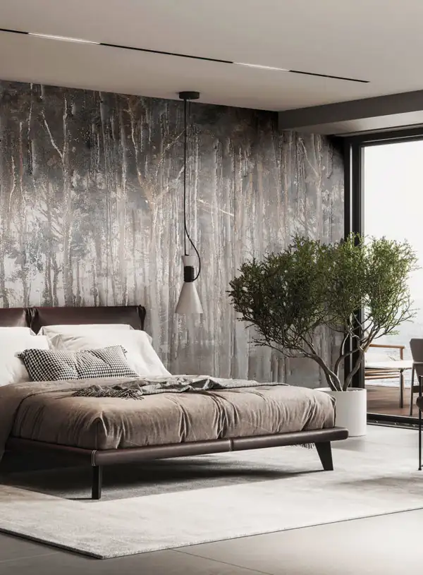 Modern bedroom with a low brown upholstered bed, white and patterned pillows, a beige blanket, a large tree in a white pot, a textured forest mural wall, and a large window showing outdoor furniture.