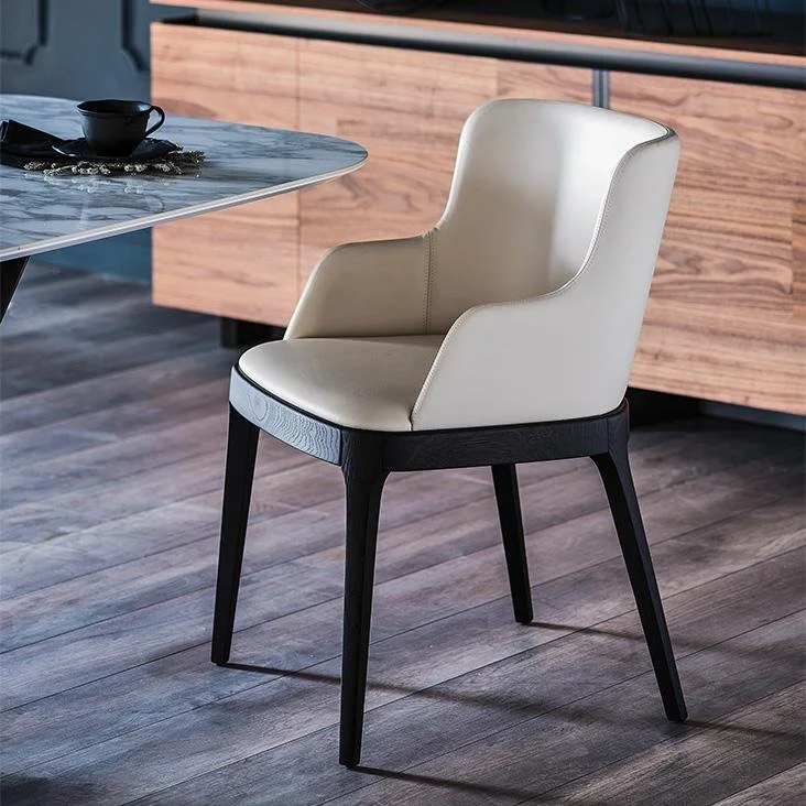 Modern dining chair with cream-colored cushioned seat and backrest, wooden dark legs, placed on a wooden floor next to a marble table with a black cup and napkin.