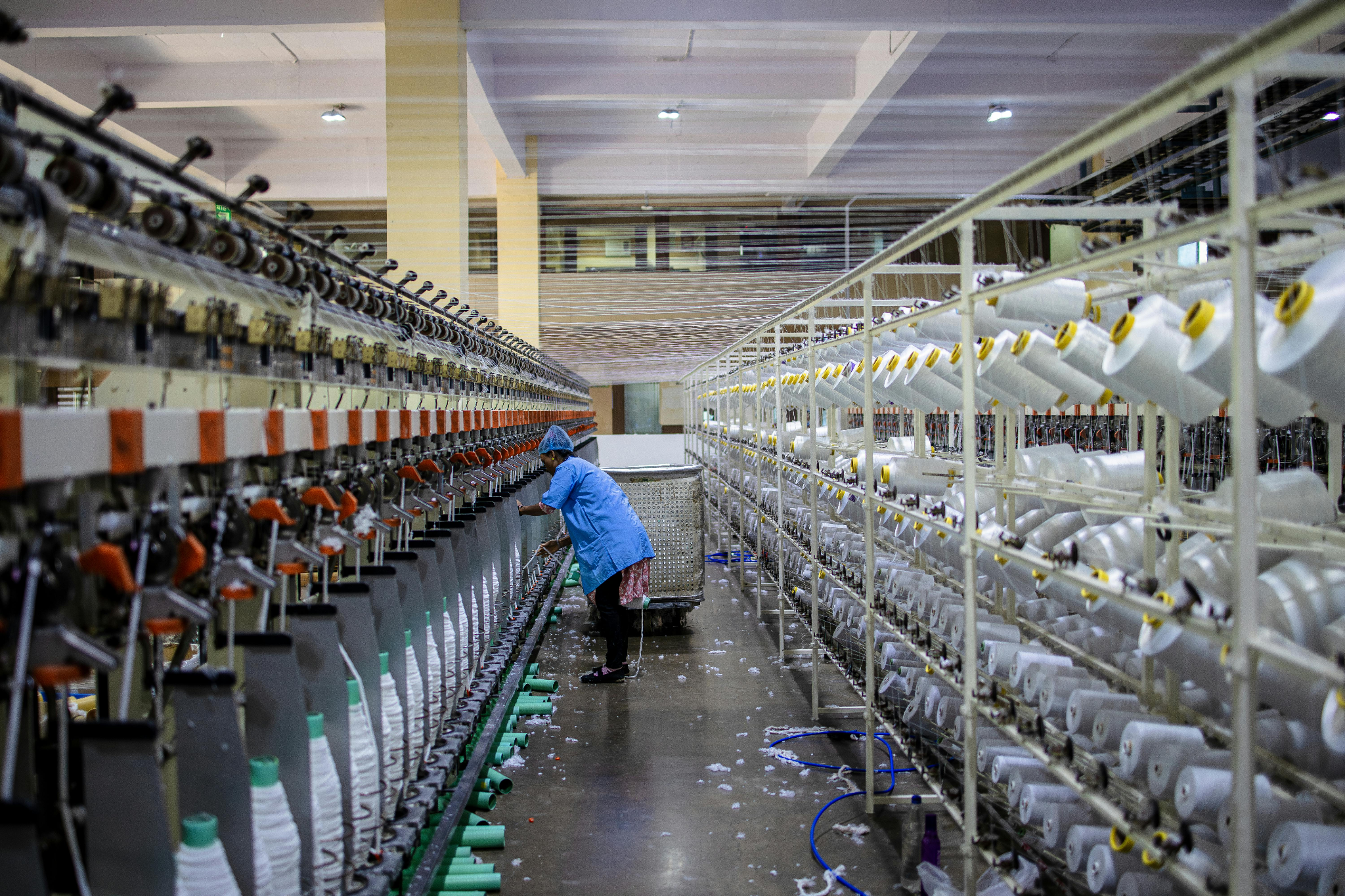 A fabric operator unspooling some thread following guidance from their Bill of Materials in Inventory Management.
