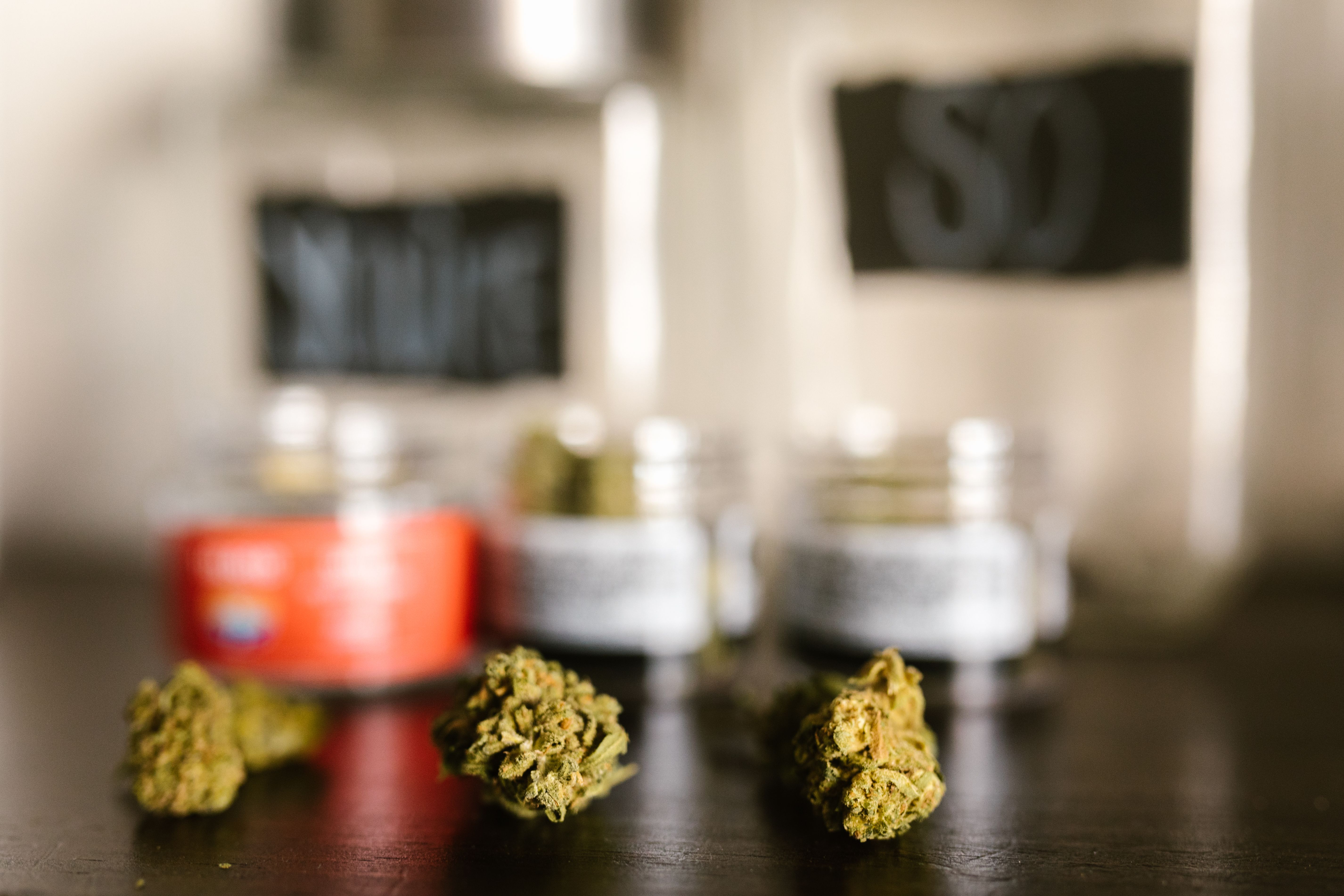 cannabis batch containers lined up on a table, each with a printed barcode tag attached.