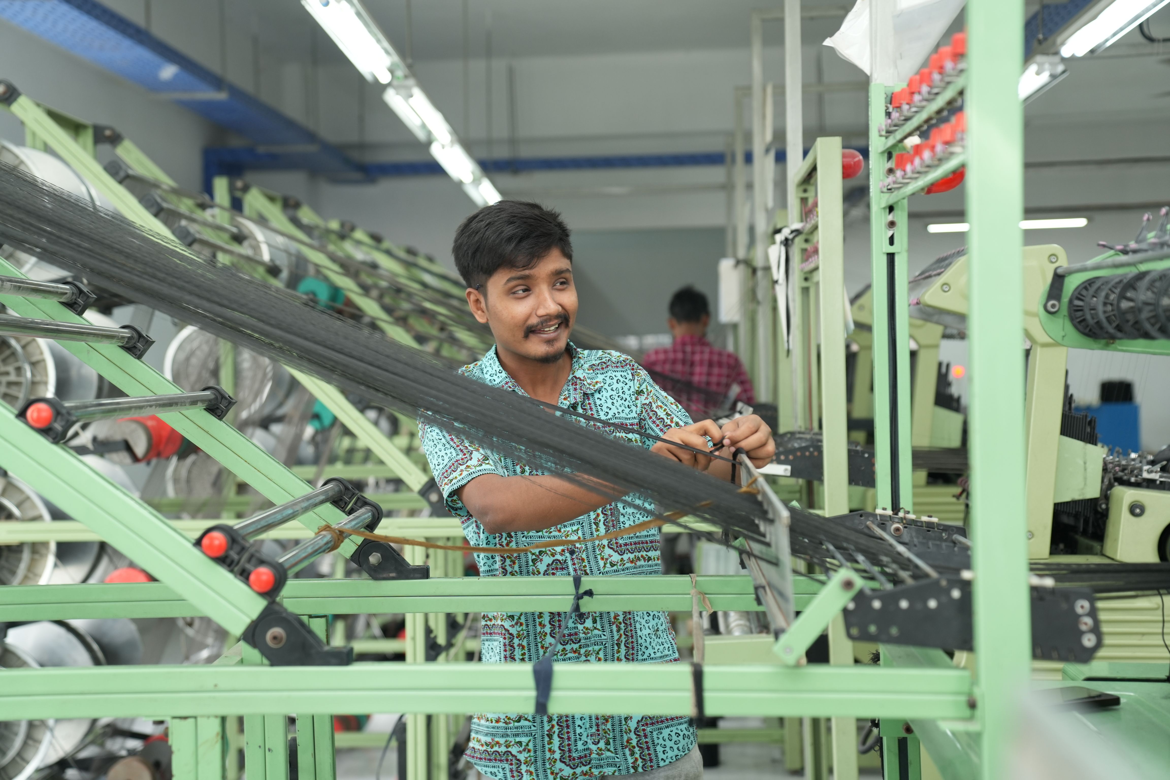 An assembly-line worker attaching a sensor to a production line for gathering data for the AI or a robot performing a quality control check of a batch of products.