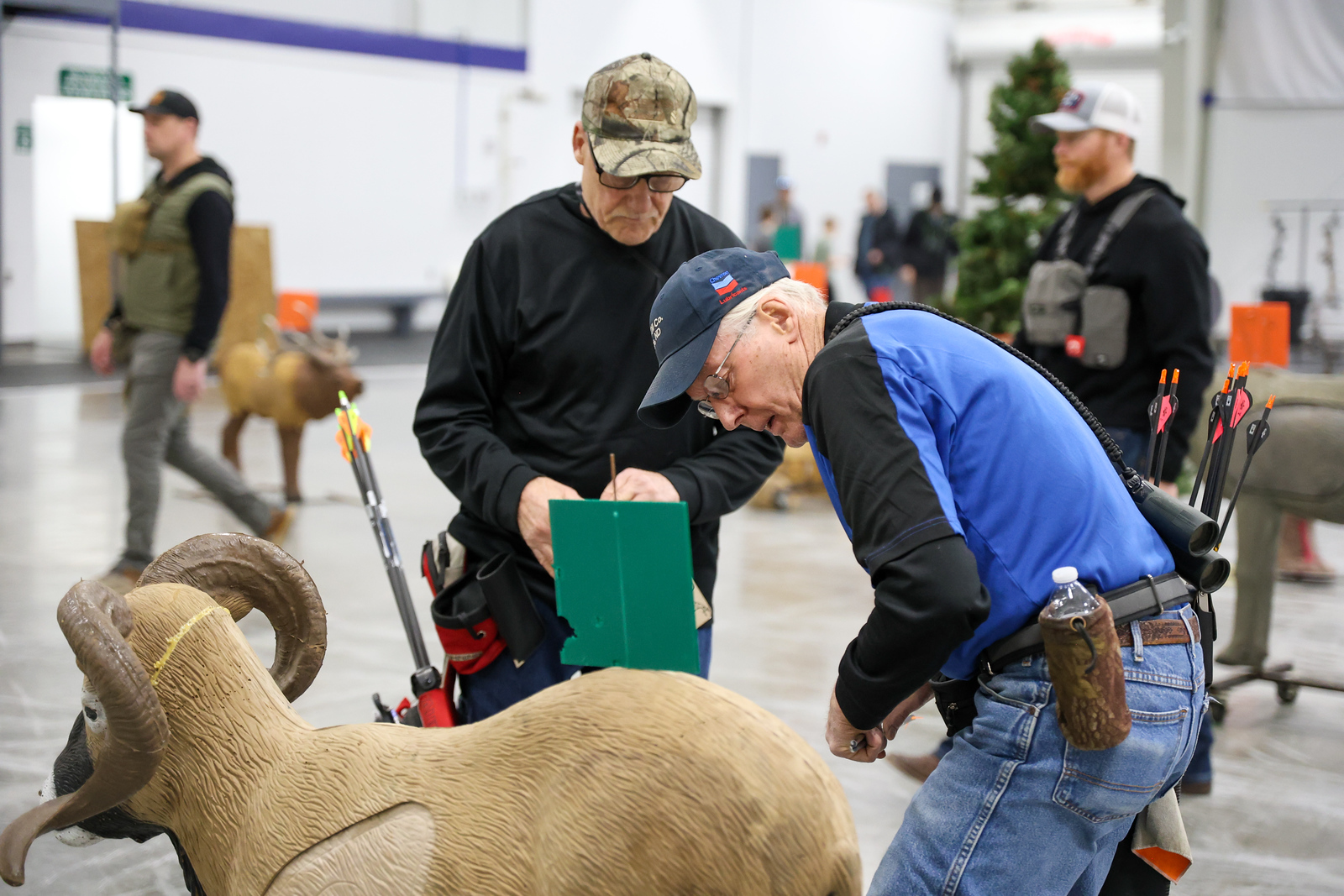 Archers scoring a shot next to a 3D animal target indoors