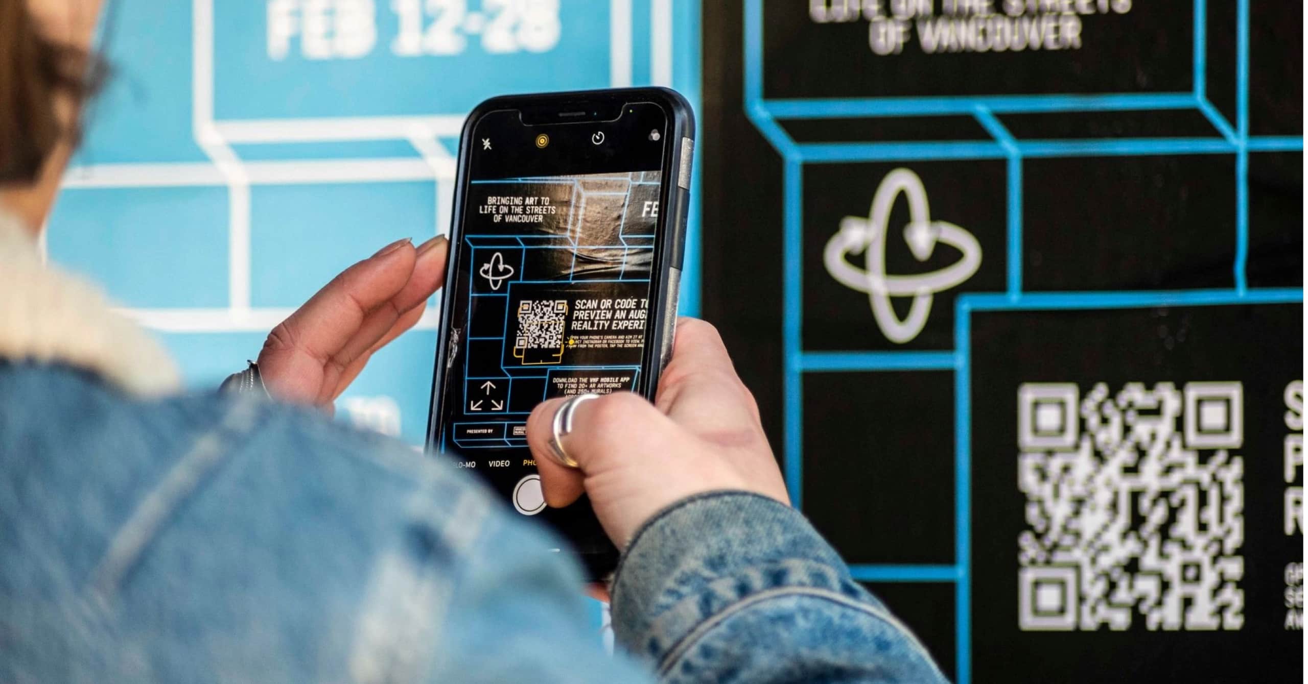 photo of man holding iPhone, scanning QR code to see AR experience