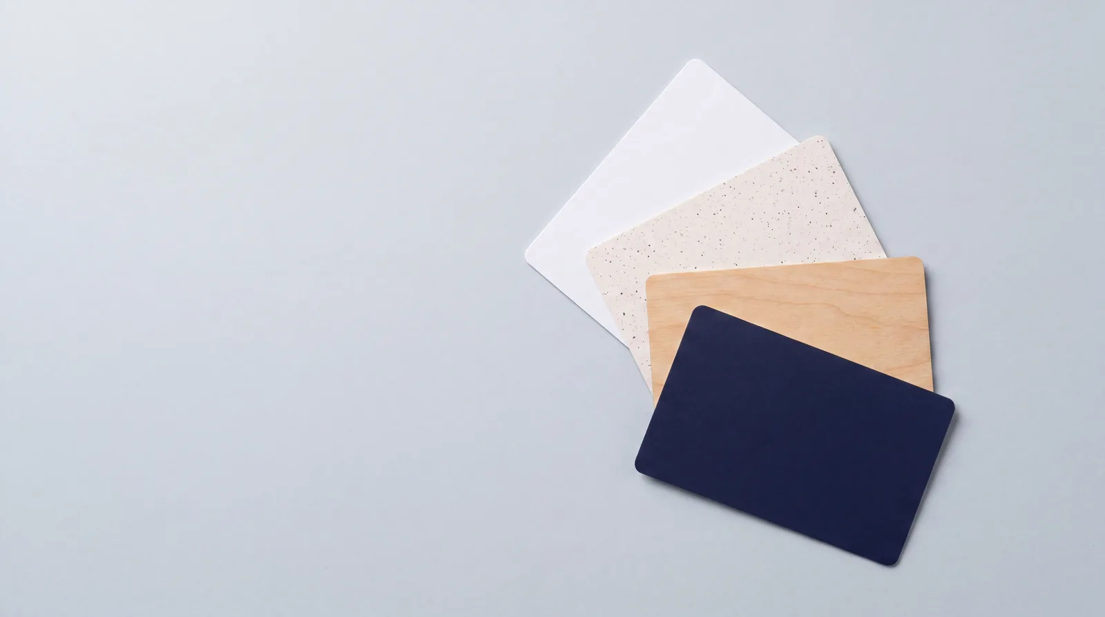 Four blank hotel key card bodies side by side: white PVC, recycled PVC, natural wood and navy PVC